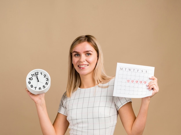 時計と彼女の期間カレンダーを保持しているスマイリー女性