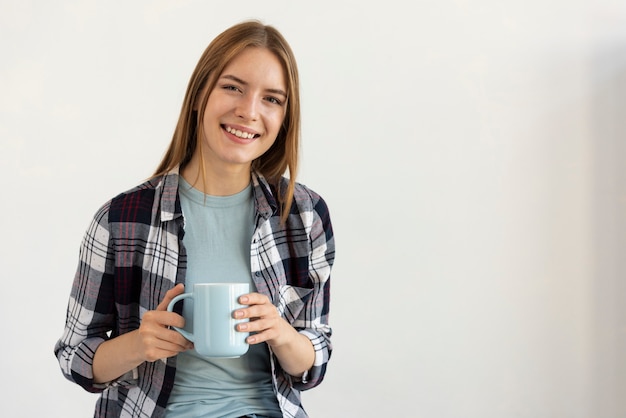 コピースペースとコーヒーのカップを保持しているスマイリーの女性