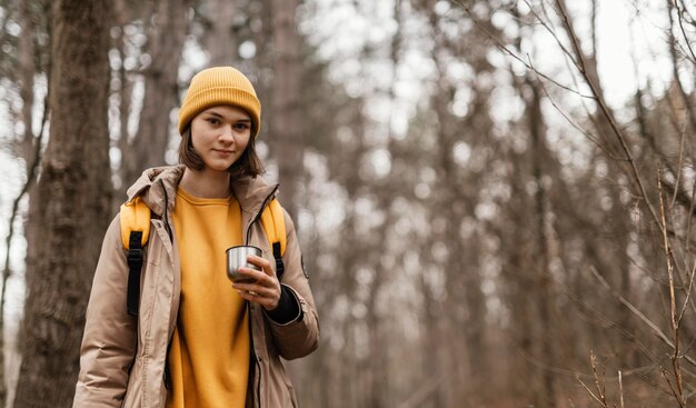 Смайлик женщина, держащая чашку в лесу