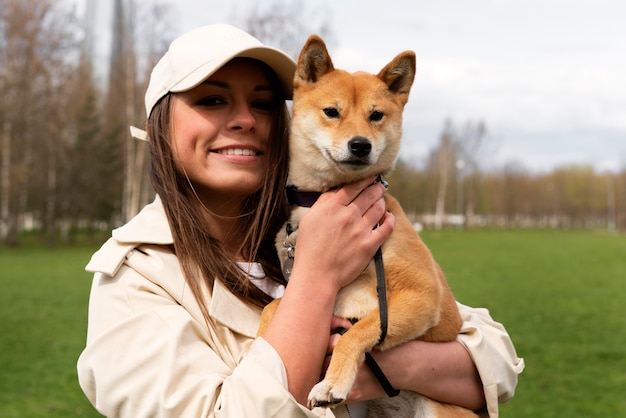 かわいい犬のミディアムショットを保持しているスマイリー女性