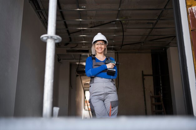 Smiley woman holding drill medium shot