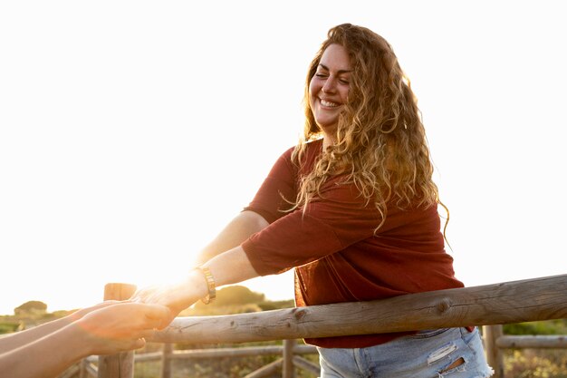 Smiley woman holding friend's hand outdoors