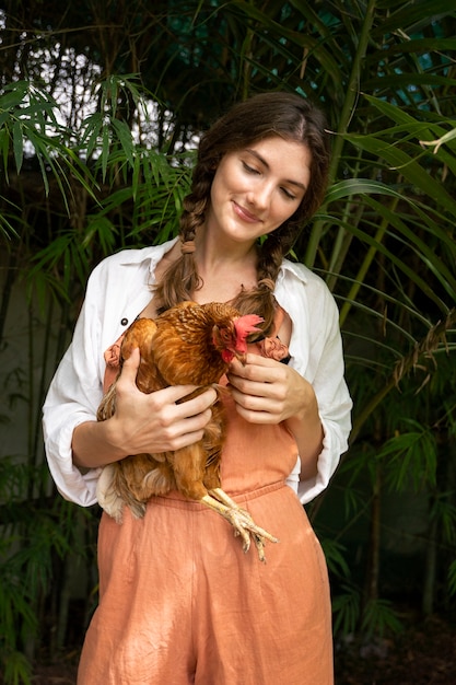 Foto gratuita vista frontale della gallina della holding della donna di smiley