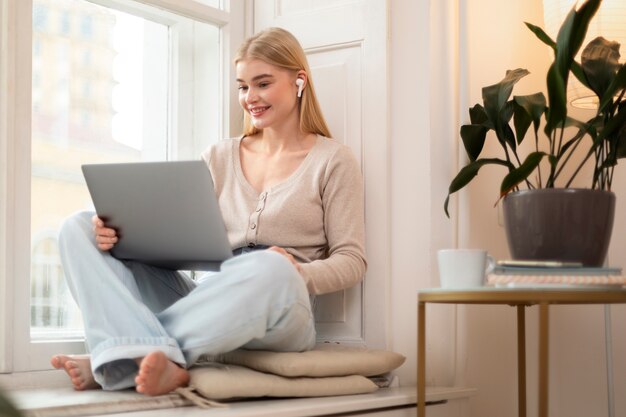 Smiley woman holding laptop full shot