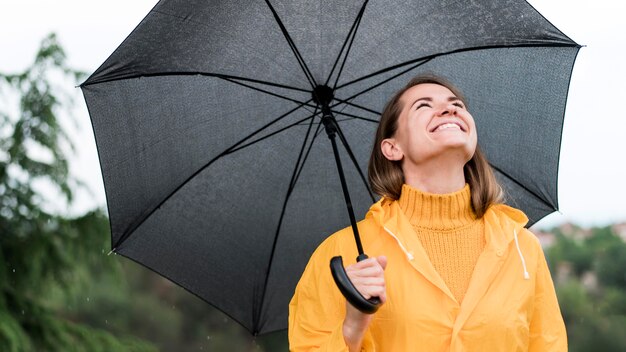 Smiley woman holding an open black umbrella