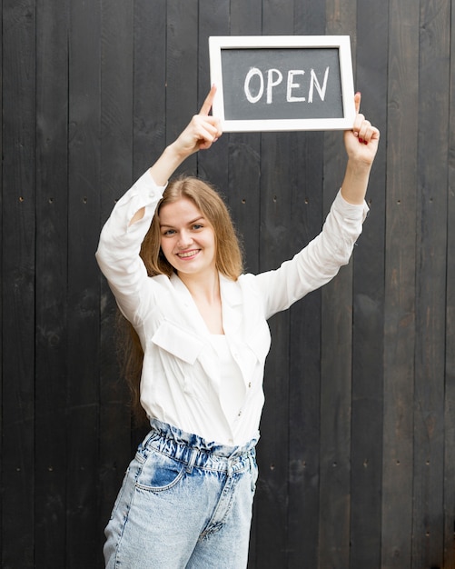 Smiley woman holding open sign