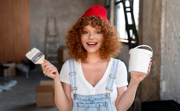 Free photo smiley woman holding paintbrush and bucket for new home decoration