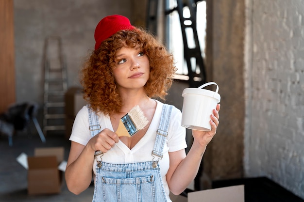 Smiley woman holding paintbrush and bucket for new home decoration