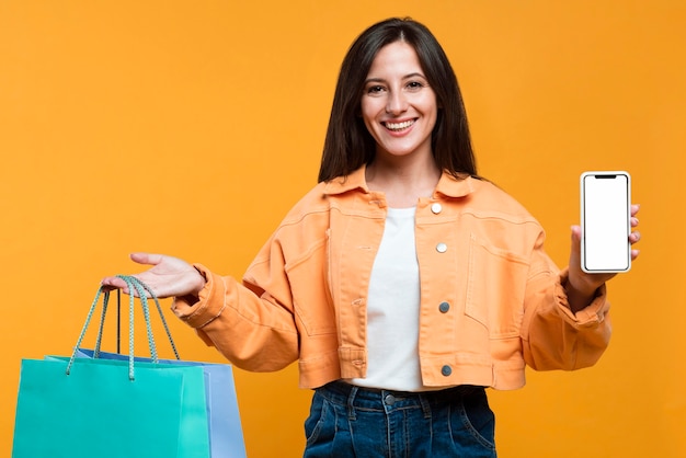 Smiley woman holding shopping bags and smartphone