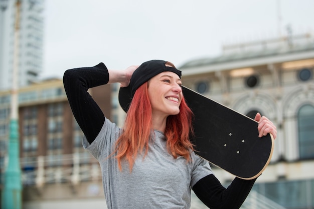 Smiley woman holding skateboard medium shot