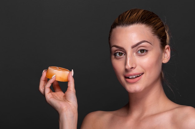Smiley woman holding skin care product