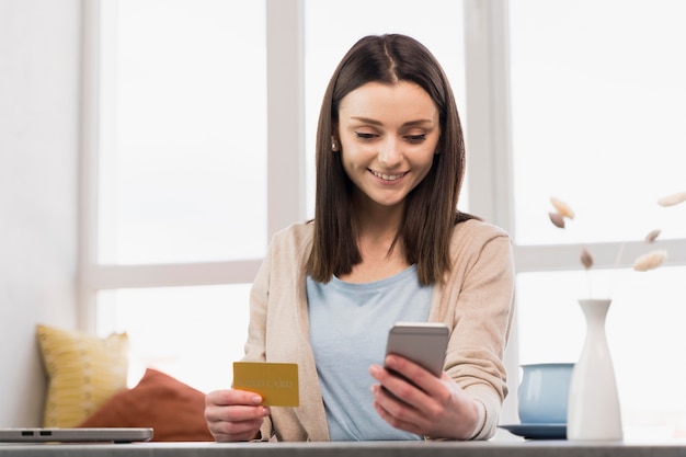 Smiley woman holding smartphone and credit card