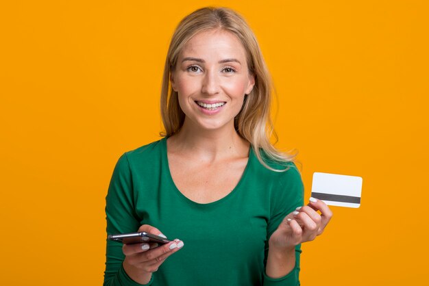 Smiley woman holding smartphone and credit card
