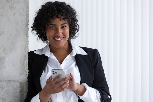 Smiley woman holding smartphone medium shot