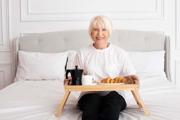 Free photo smiley woman holding a tray in the bedroom