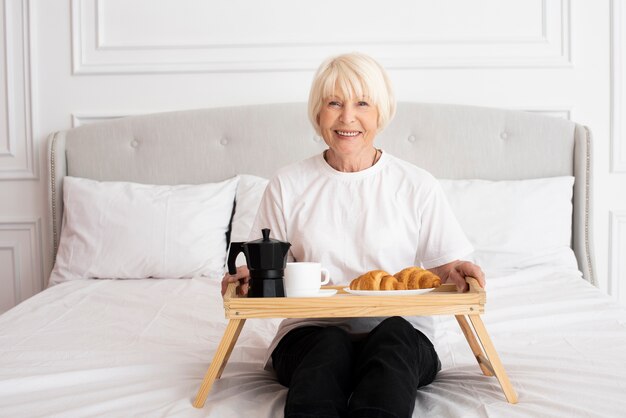 Smiley woman holding a tray in the bedroom