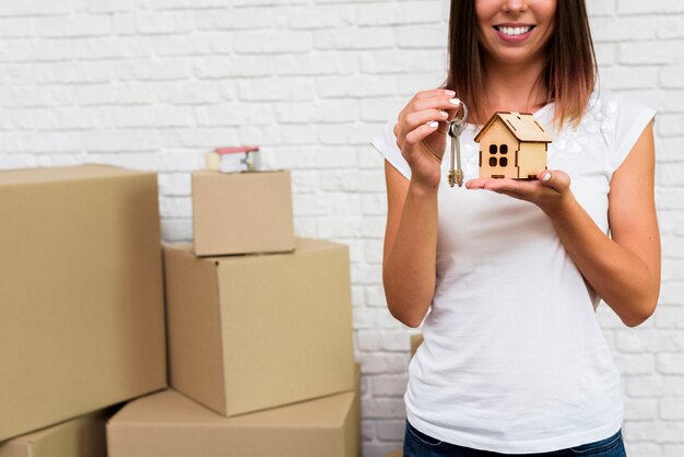 Smiley woman holding a wooden cottage and keys