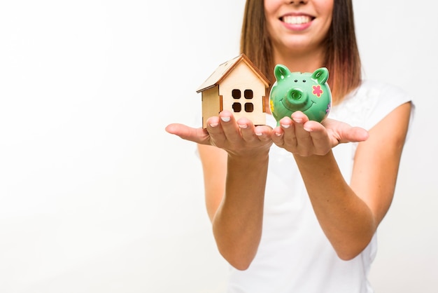 Smiley woman holding a wooden cottage and a piggy back