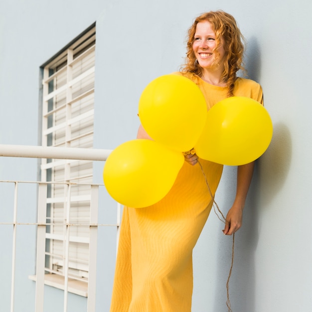 Бесплатное фото Улыбающаяся женщина с желтыми воздушными шарами