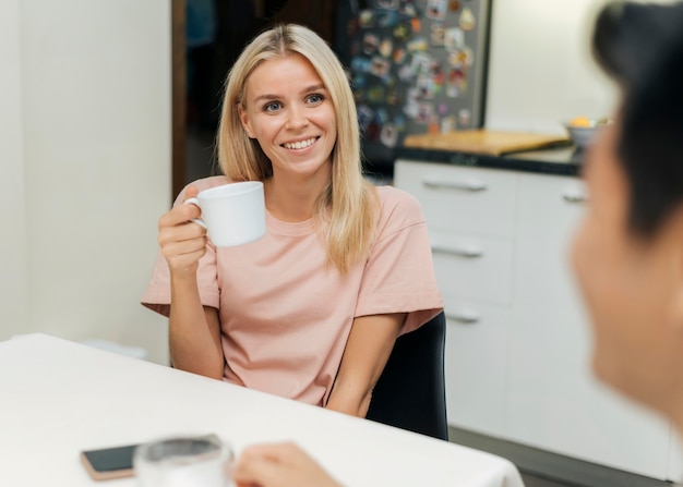 Smiley woman at home during the pandemic having a cup of coffee with her boyfriend