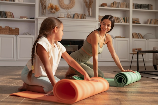 Smiley woman and kid with yoga mat full shot