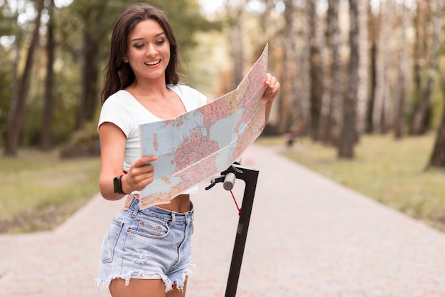 Smiley woman looking at map next to electric scooter