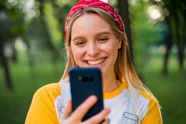 Smiley woman looking at smartphone outdoors