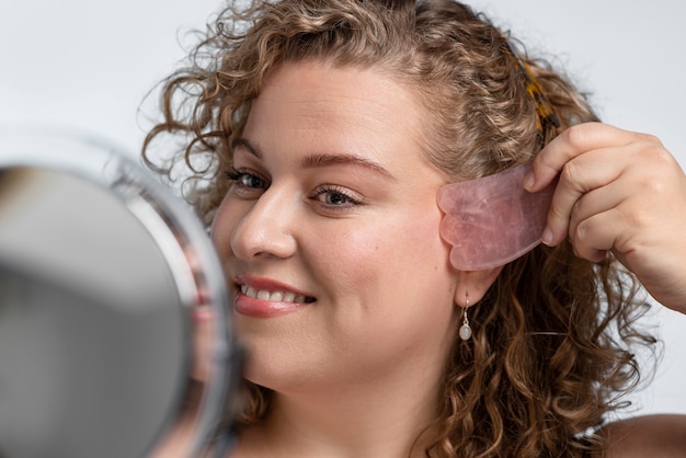 Smiley woman massaging face with gua sha tool