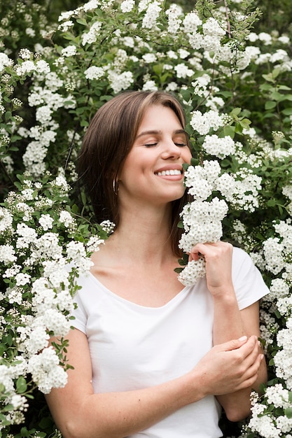 Smiley woman in nature smelling flowers