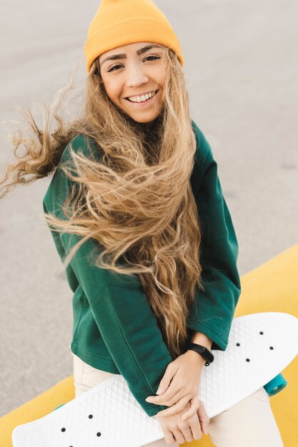 Foto gratuita donna sorridente all'aperto con skateboard