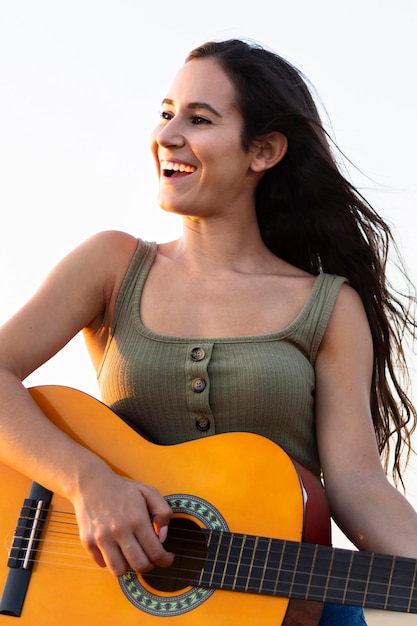 smiley woman playing guitar while outdoors in nature