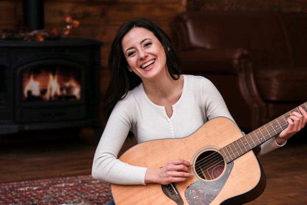 Free photo smiley woman playing guitar