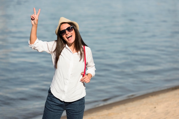 Smiley woman posing at the beach and making peace sign