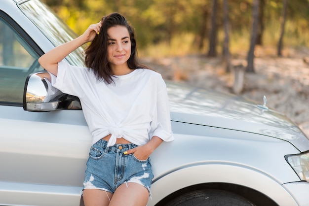 Donna di smiley che posa vicino all'automobile