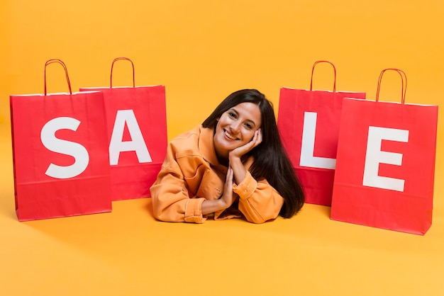 Free photo smiley woman posing in between sale shopping bags