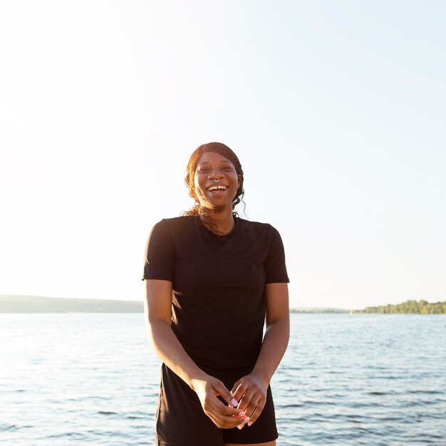 Smiley woman posing while exercising by the lake