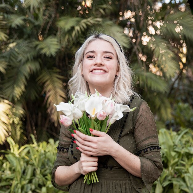 Smiley woman posing while holding bouquet of flowers