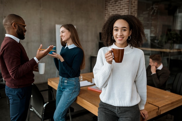 Smiley woman posing while holding coffee mug during an office meeting