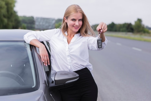 スマイリー女性が車のキーでポーズ