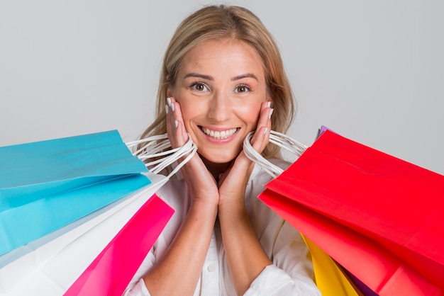 Free photo smiley woman posing with many colorful shopping bags