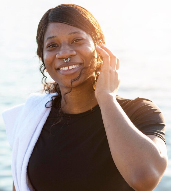 Smiley woman posing with towel on shoulder after exercising