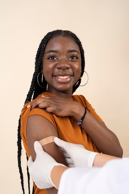 Free photo smiley woman receiving sticker on arm after getting a vaccine