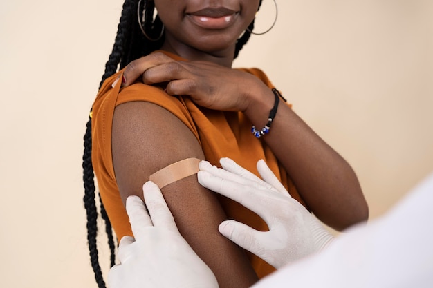 Free photo smiley woman receiving sticker on arm after getting a vaccine