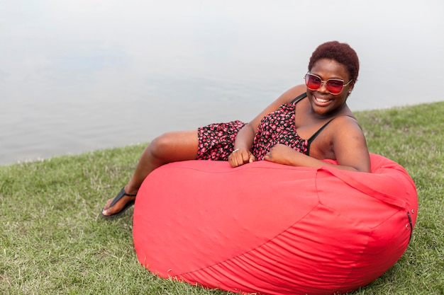 Free photo smiley woman relaxing outside on bean bag