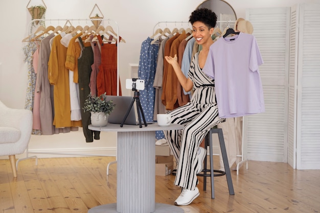 Foto gratuita donna sorridente che vende vestiti a tutto campo