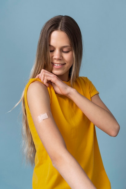 Улыбающаяся женщина показывает руку с наклейкой после вакцинации