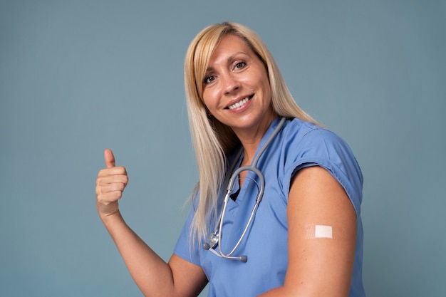 Foto gratuita donna sorridente che mostra il braccio con un adesivo dopo aver ricevuto un vaccino