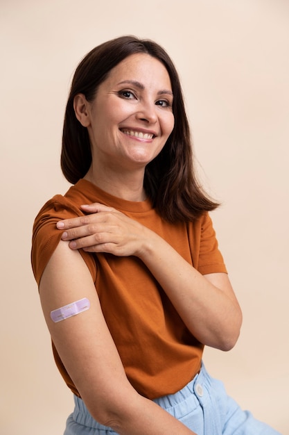 Smiley woman showing sticker on arm after getting a vaccine