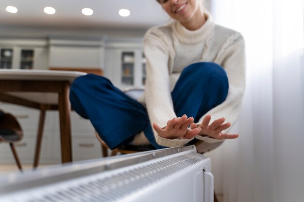 Smiley woman sitting near heater at home