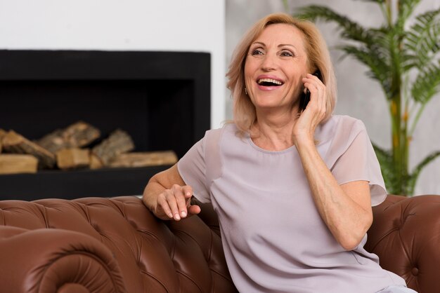 전화 통화하는 동안 소파에 앉아 웃는 여자